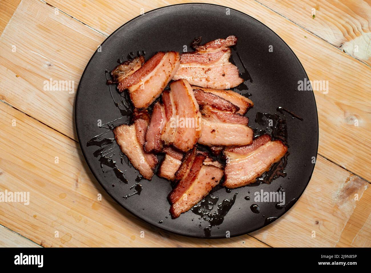 Thin sliced fried pork meat on a black ceramic plate Stock Photo