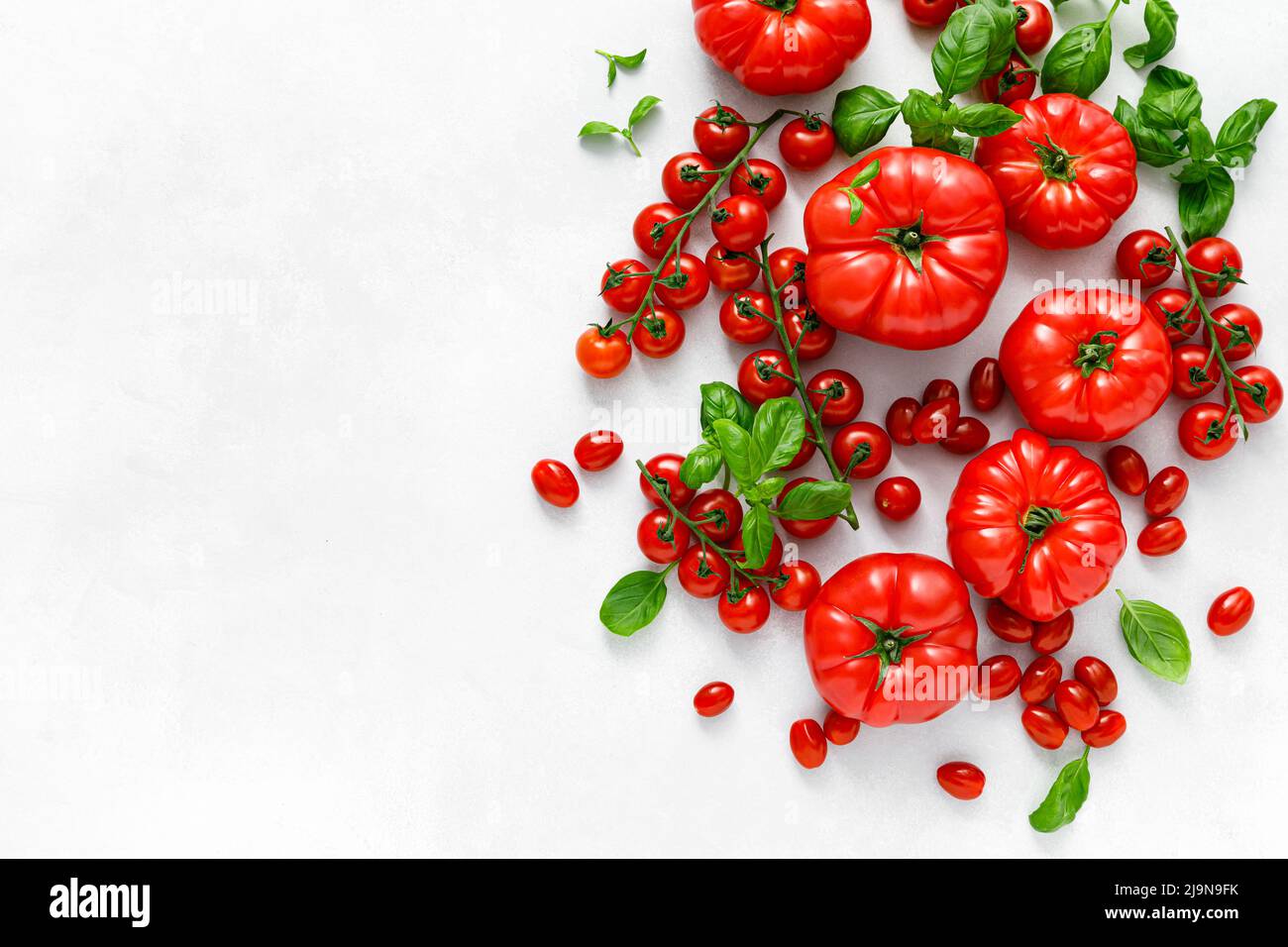Tomatoes and basil on white background, top view, flat lay Stock Photo