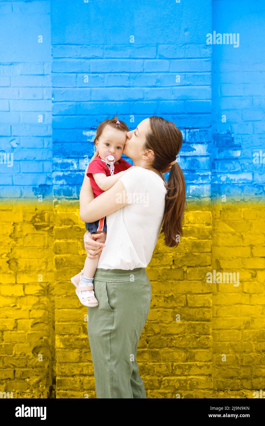 Loving mother kissing her daughter in front of an old wall Stock Photo
