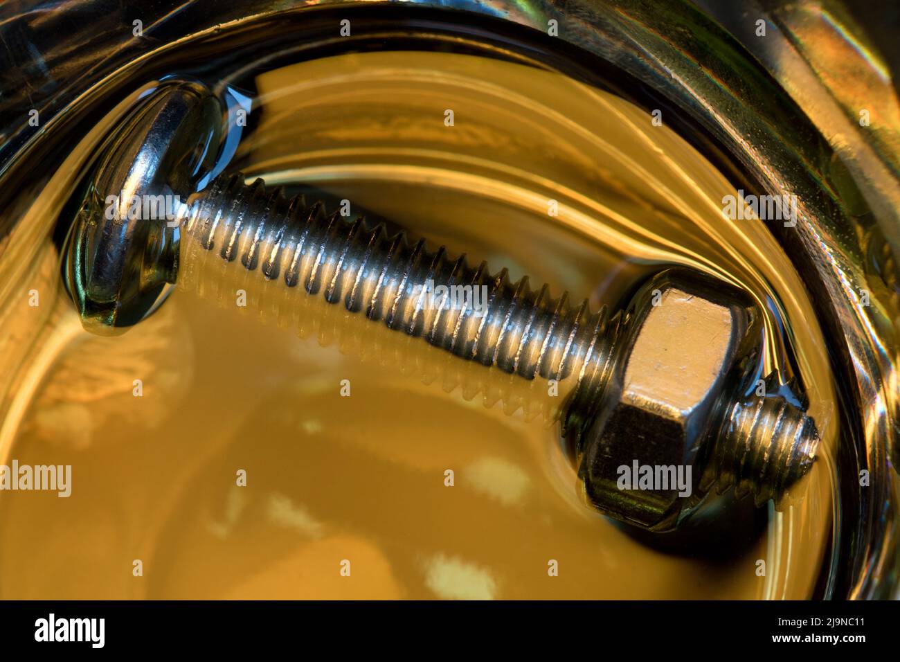 Metallic nuts and bolts in lubrication oil Stock Photo