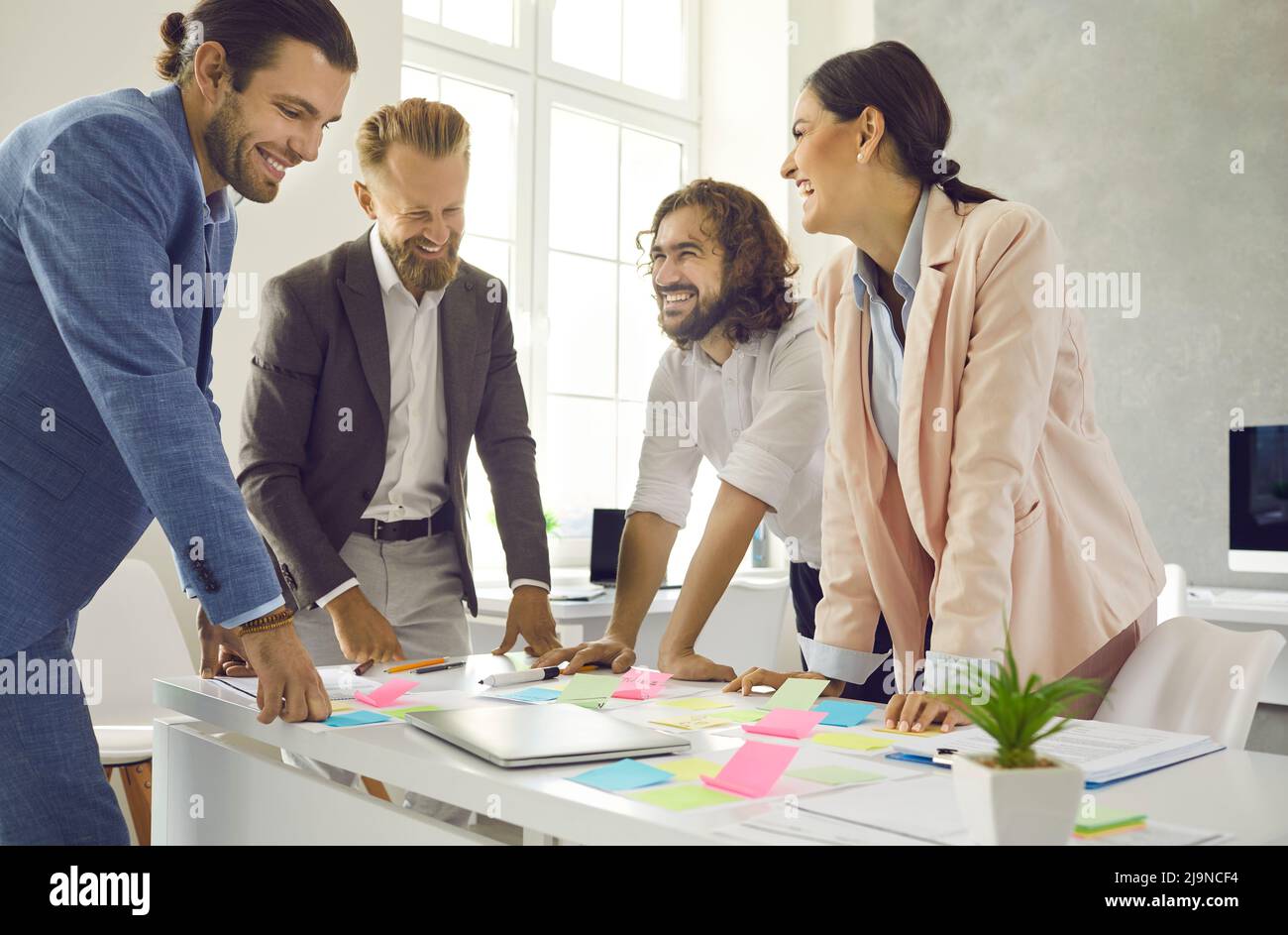 Creative colleagues write notes on colorful stickers while developing business project in office. Stock Photo