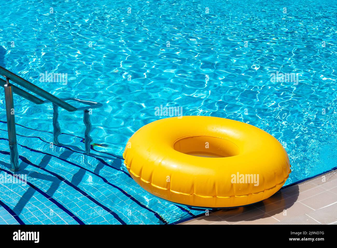 Yellow ring floating in refreshing blue swimming pool Stock Photo - Alamy