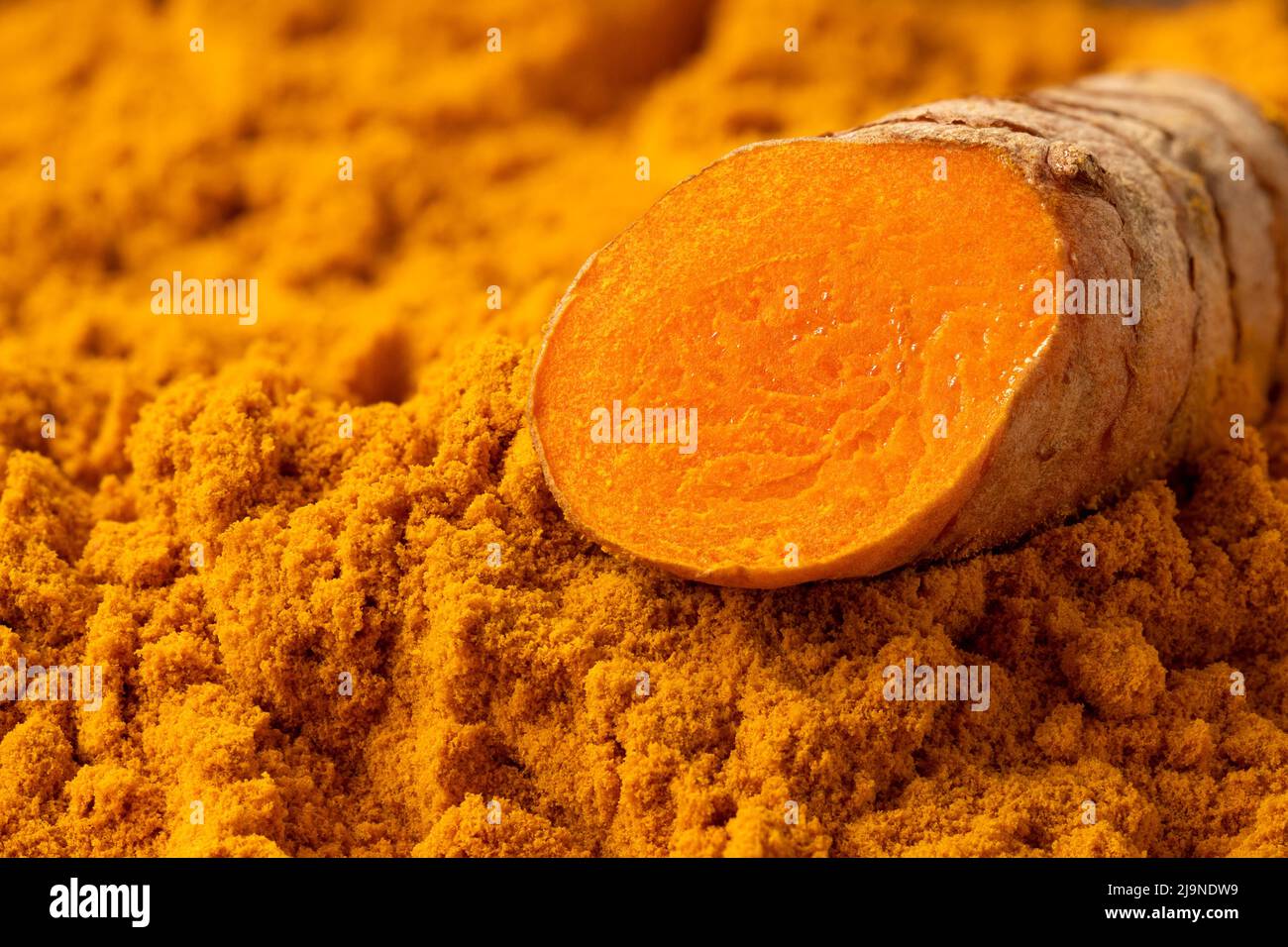Sliced turmeric root on ground turmeric. Stock Photo