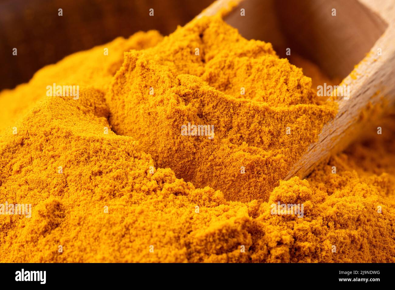 Detail of ground turmeric with wooden spoon. Stock Photo