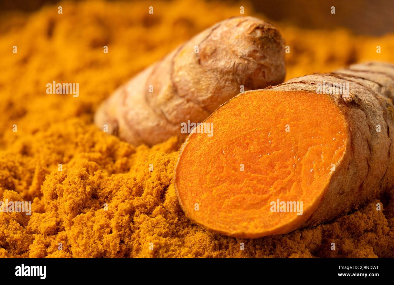 Sliced turmeric root on ground turmeric. Stock Photo