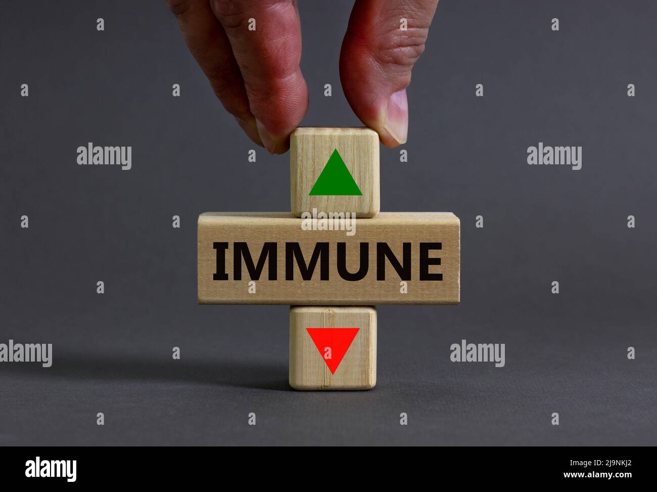 Growth of immune symbol. Doctor holds a wooden cube with up icon. Wooden block with yhe concept wordIimmune. Beautiful grey table grey background. Med Stock Photo