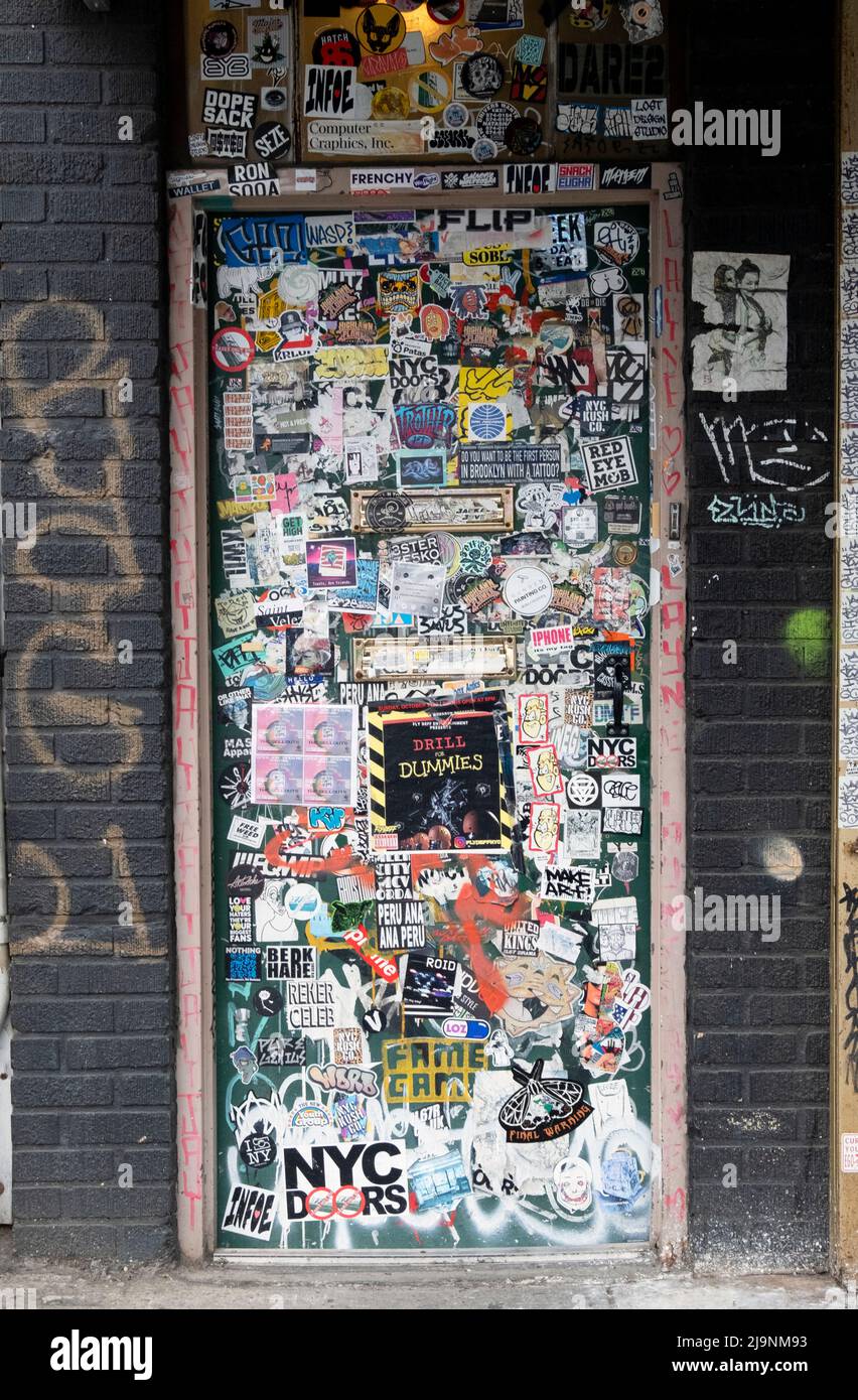 A doorway completely covered in stickers, street art, graffiti and tags