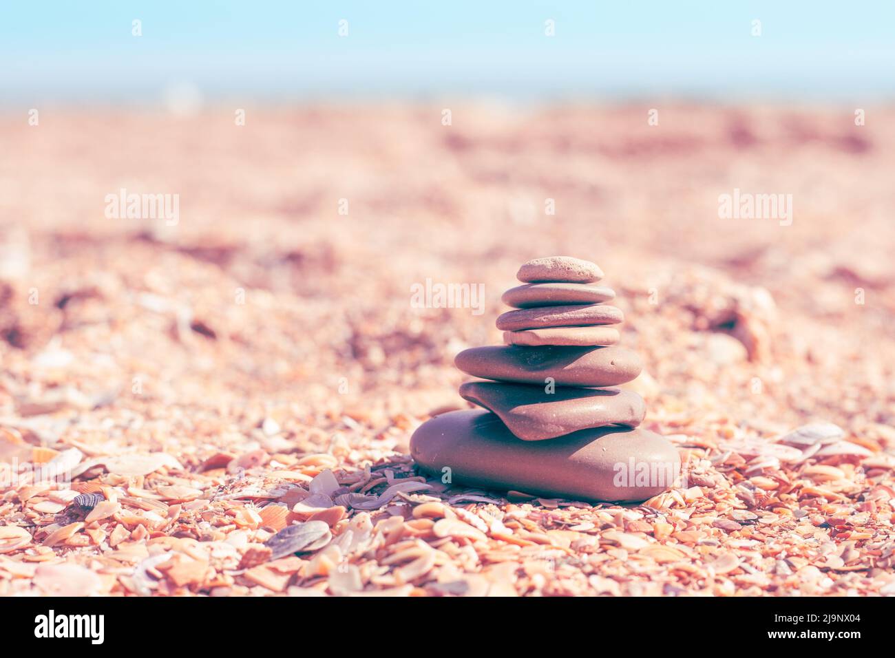 stones are stacked in a pyramid on a sandy sea shore, selective focus, copy space. Relaxation and balance. Stock Photo