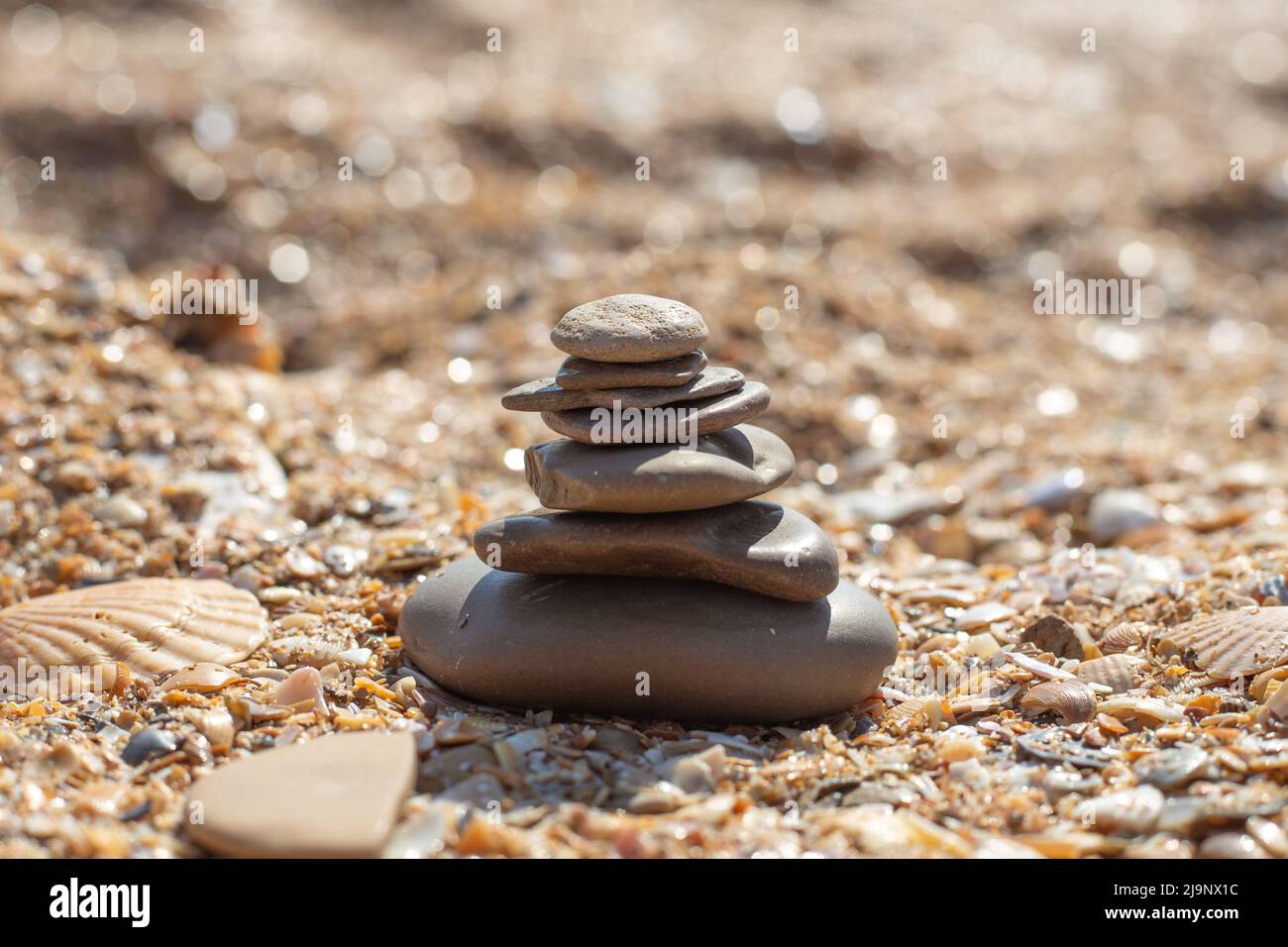 Pyramid of stones laid out on a sandy beach, selective focus. Relaxation and balance. Stock Photo