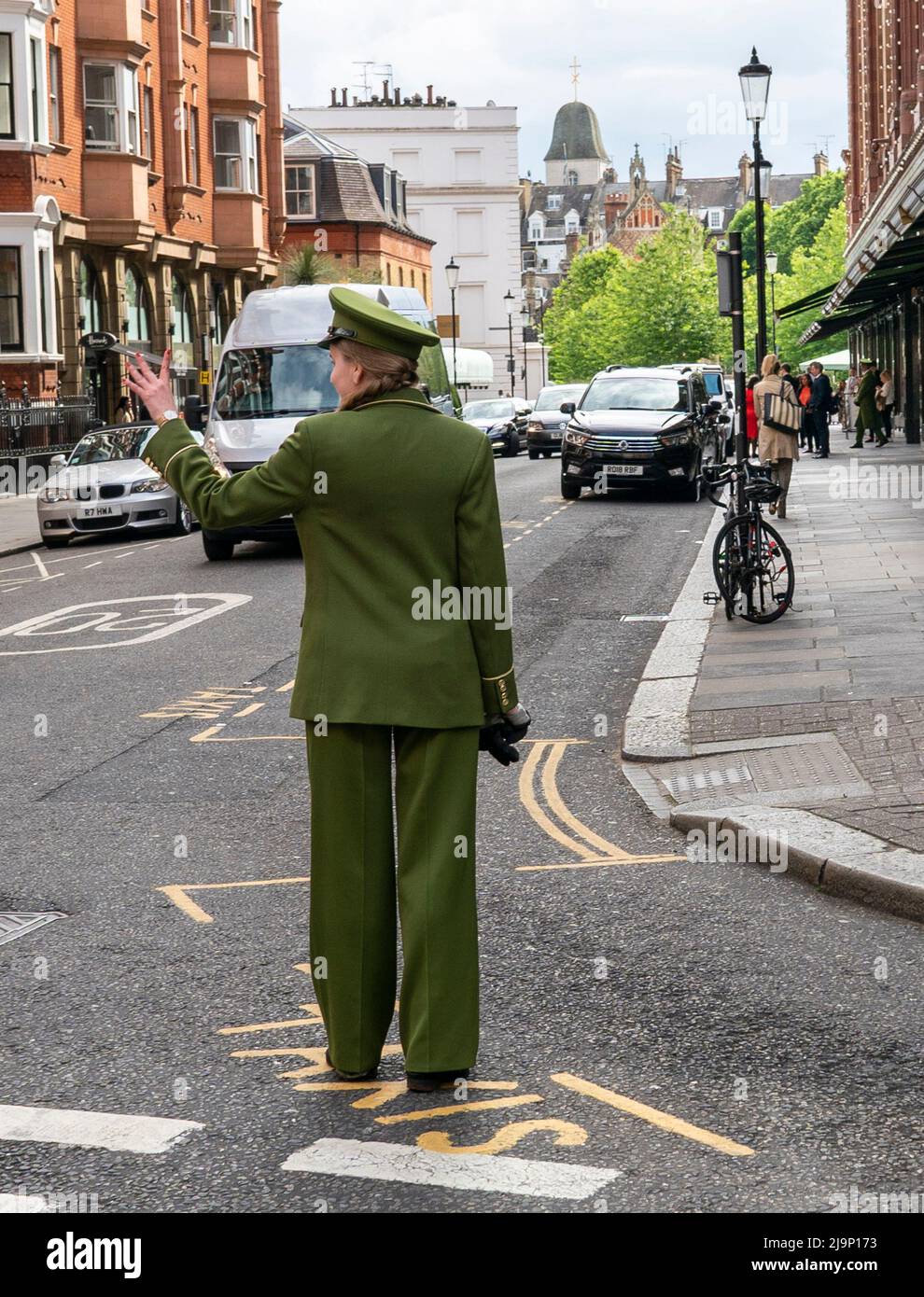 A Female Harrods doorman hails a cab outside the iconic department