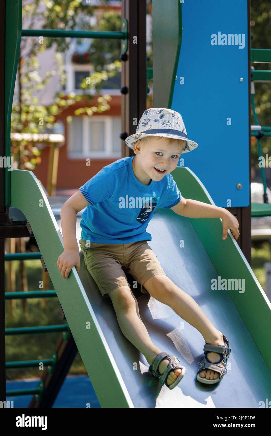 Little boy riding on the slide on children playground. Concept of child development, sports and