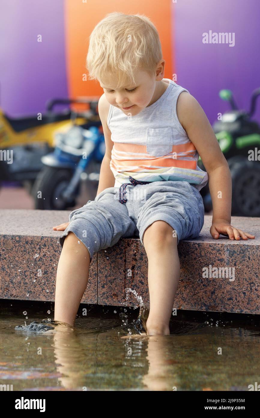boy barefoot Little barefoot boy plays with water near the fountain in a big city during  the summer heat. They escape from the summer heat Stock Photo - Alamy