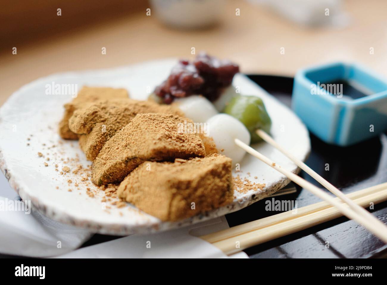 A plate of assorted traditional Japanese rice cake desserts: dango skewers topped with adzuki (red bean) paste and bean powder-coated warabi mochi. Stock Photo