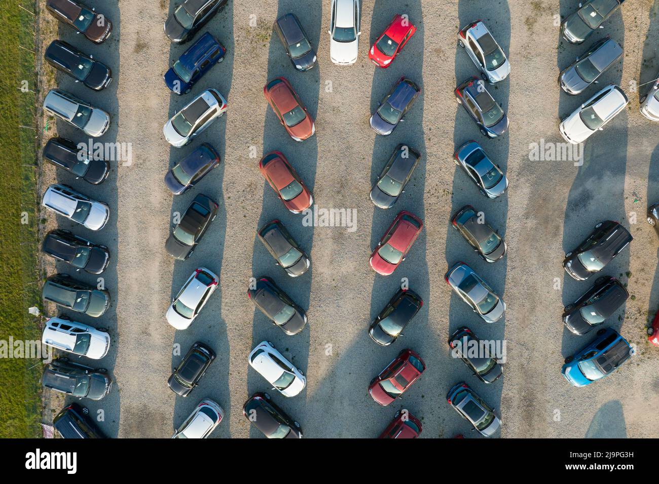 Aerial view of many colorful cars parked on dealer parking lot for sale