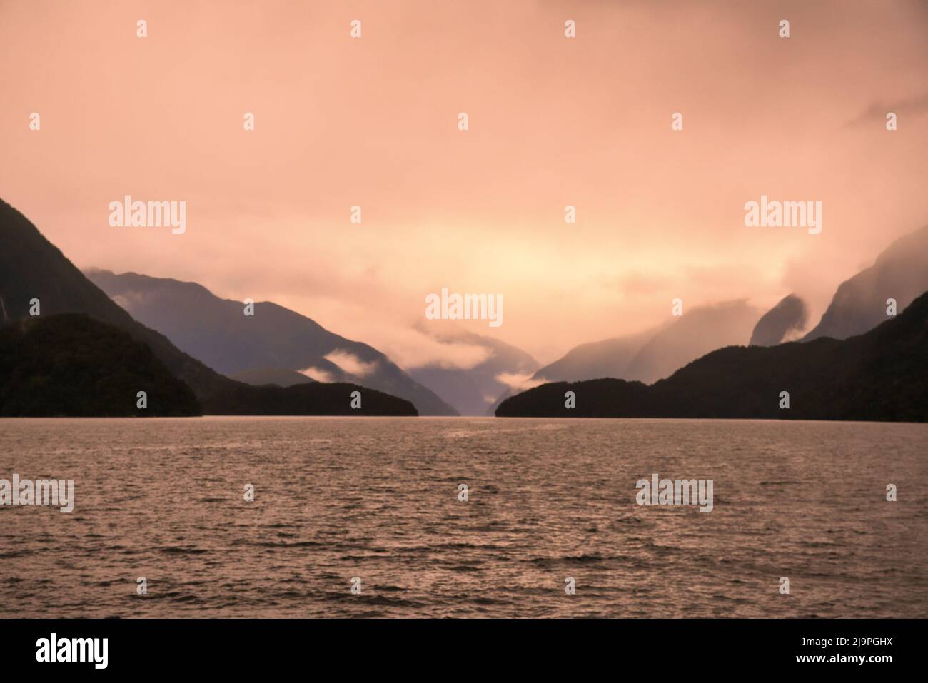 The mountains silhouetted in the murky atmosphere on a bad weather day in the fjord Stock Photo