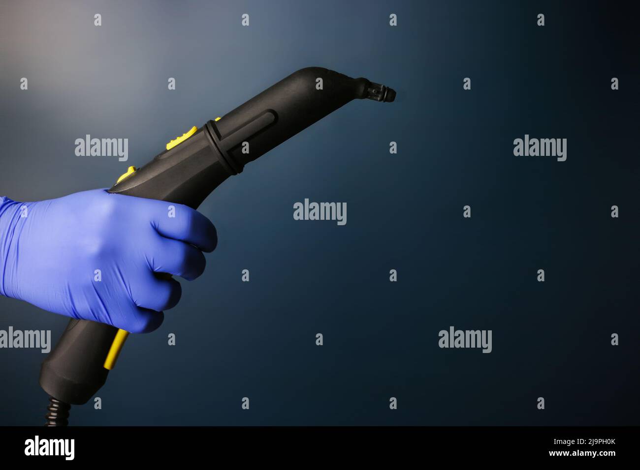 Steam cleaner in hand with hot steam on an isolated dark background