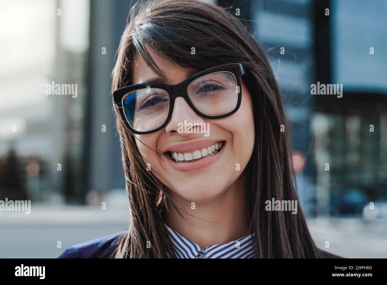 Young business woman working outside with office buildings on background - Focus on face Stock Photo