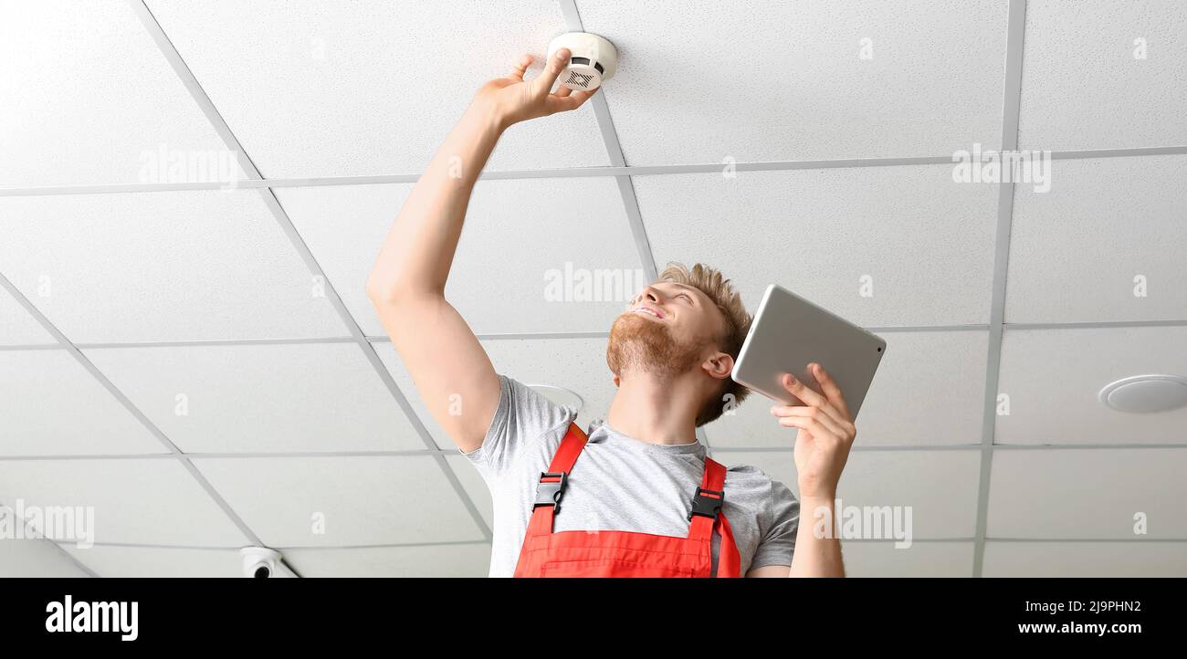 Technician installing smart home security system in room Stock Photo