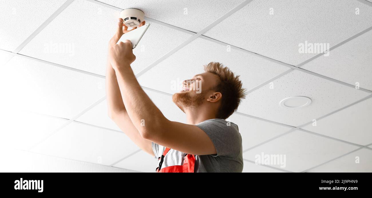 Technician installing smart home security system in room Stock Photo