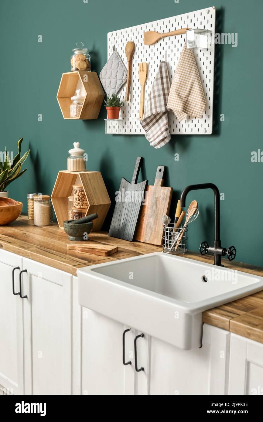 Cutting boards with kitchen utensils and sink on counters near green ...