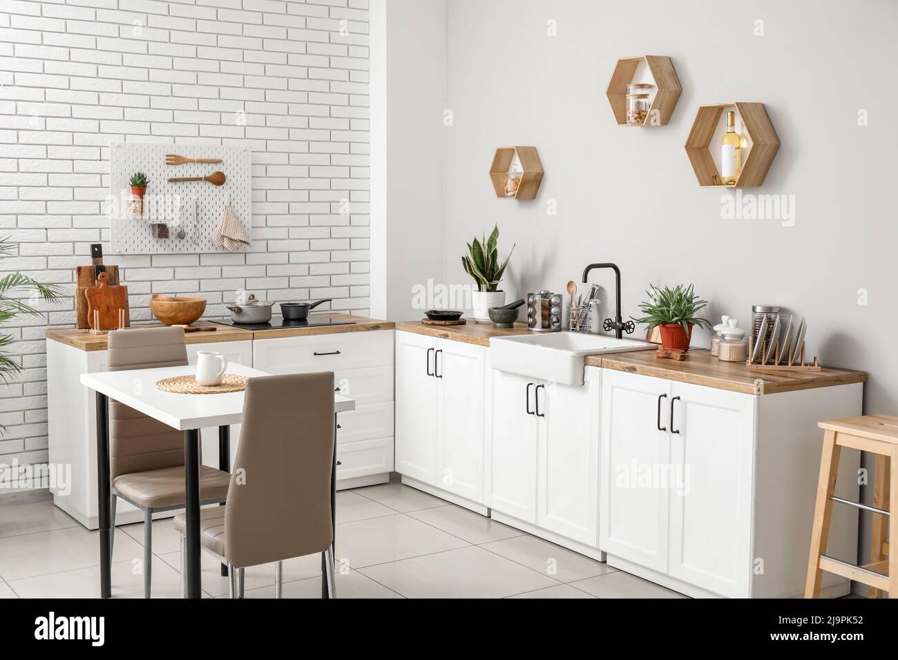 Interior of light kitchen with dining table, counters and utensils ...