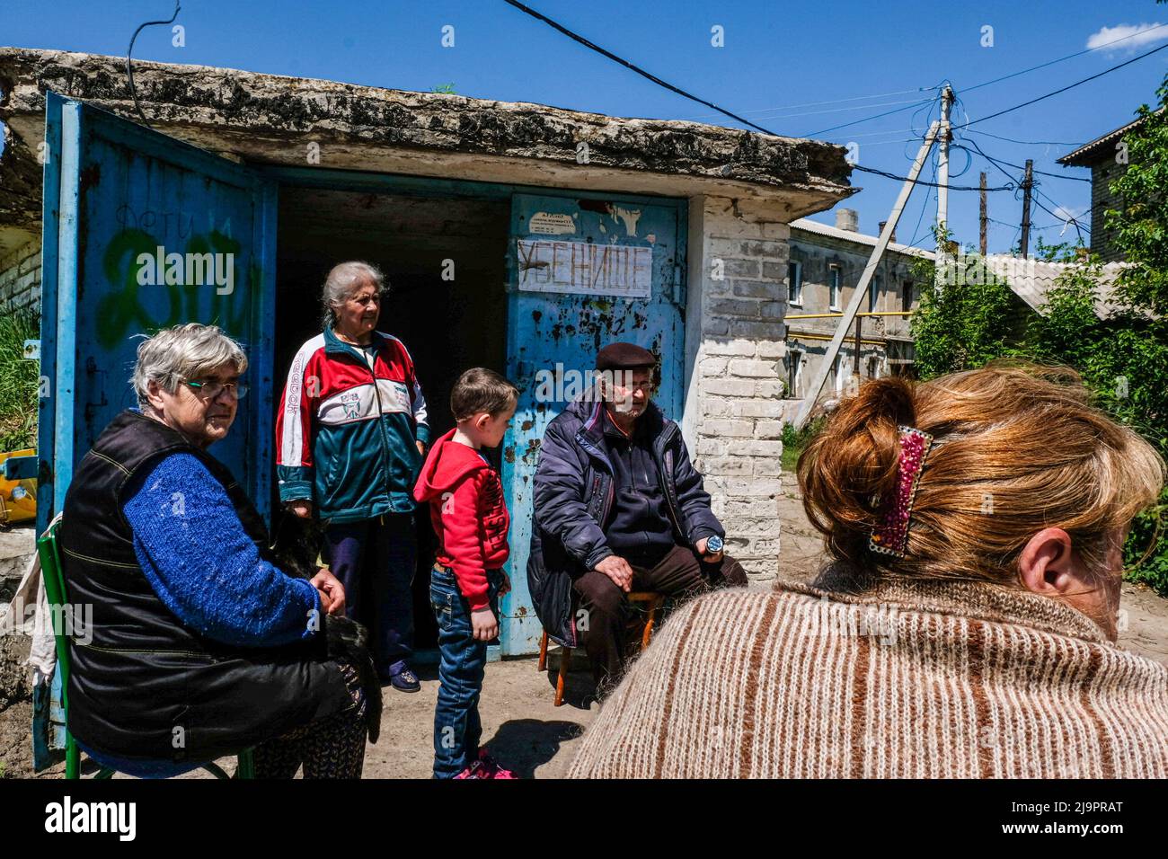 People sitting in front of a bunker where they leave in the outskirts of the city. Lysychansík, Luhansk region. 23 May 2022 Lysychansk is an elongated city on the high right bank of the Donets River in the Luhansk region. The city is part of a metropolitan area that includes Severodonetsk and Rubizhne; the three towns together constitute one of Ukraine's largest chemical complexes. The town is about 7 km from the frontline, and Russian troops are moving towards it, the city, like Severodonetsk, is almost isolated. Russian are trying to occupy the main road that connect Lysychansk to Kramatorsk Stock Photo