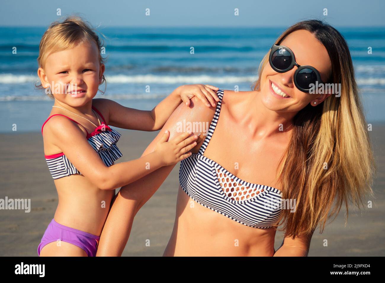 daughter and mother sunbathing on the beach Stock Photo