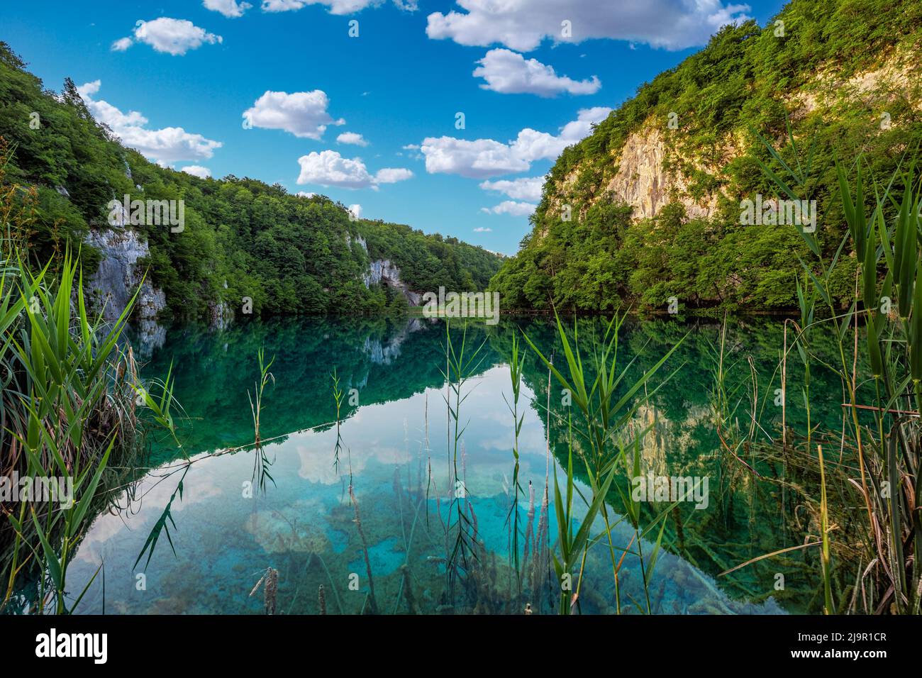Plitvice, Croatia - Reflecting Plitvice Lakes National Park on a bright summer day with crystal clear turquoise water, blue sky and clouds and green s Stock Photo