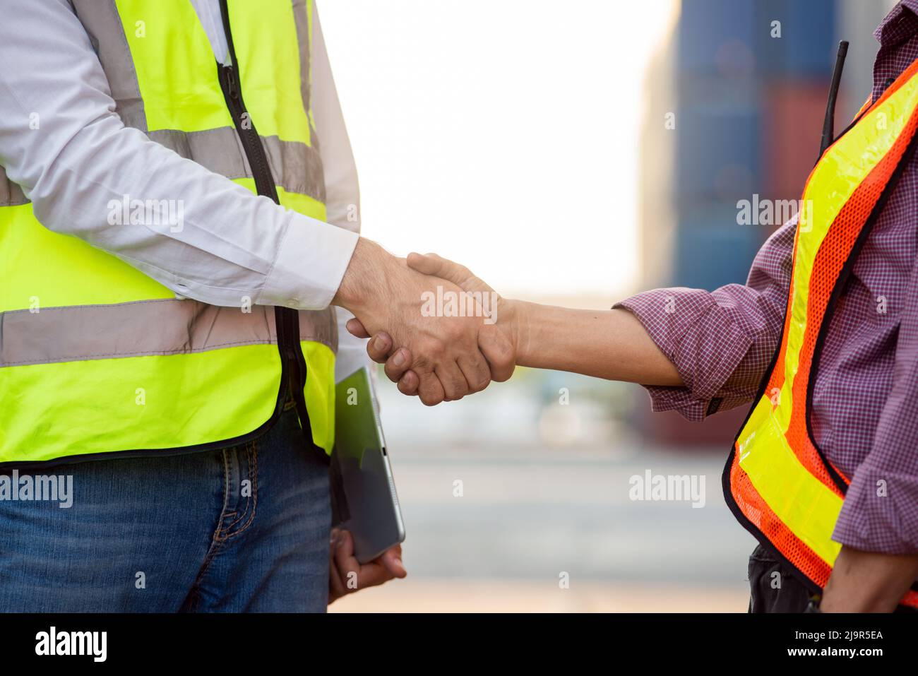 Businessman and engineers working successful handshake together into container for loading. Industrial and logistic concept Stock Photo