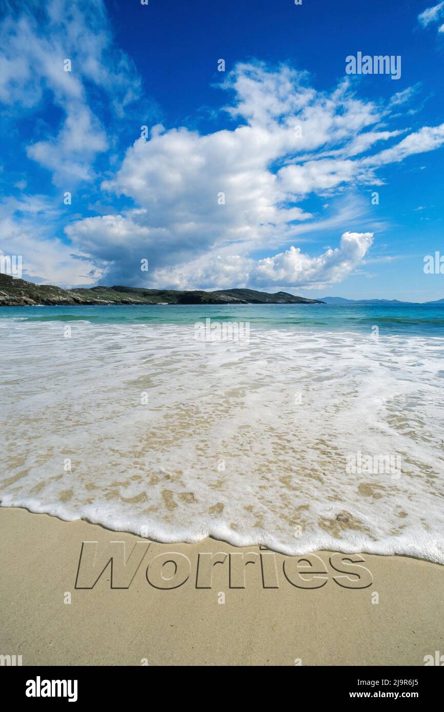 Concept image - to illustrate washing away stress by taking a relaxing seaside vacation as waves on a sandy beach wash away the word 'worries'. Stock Photo