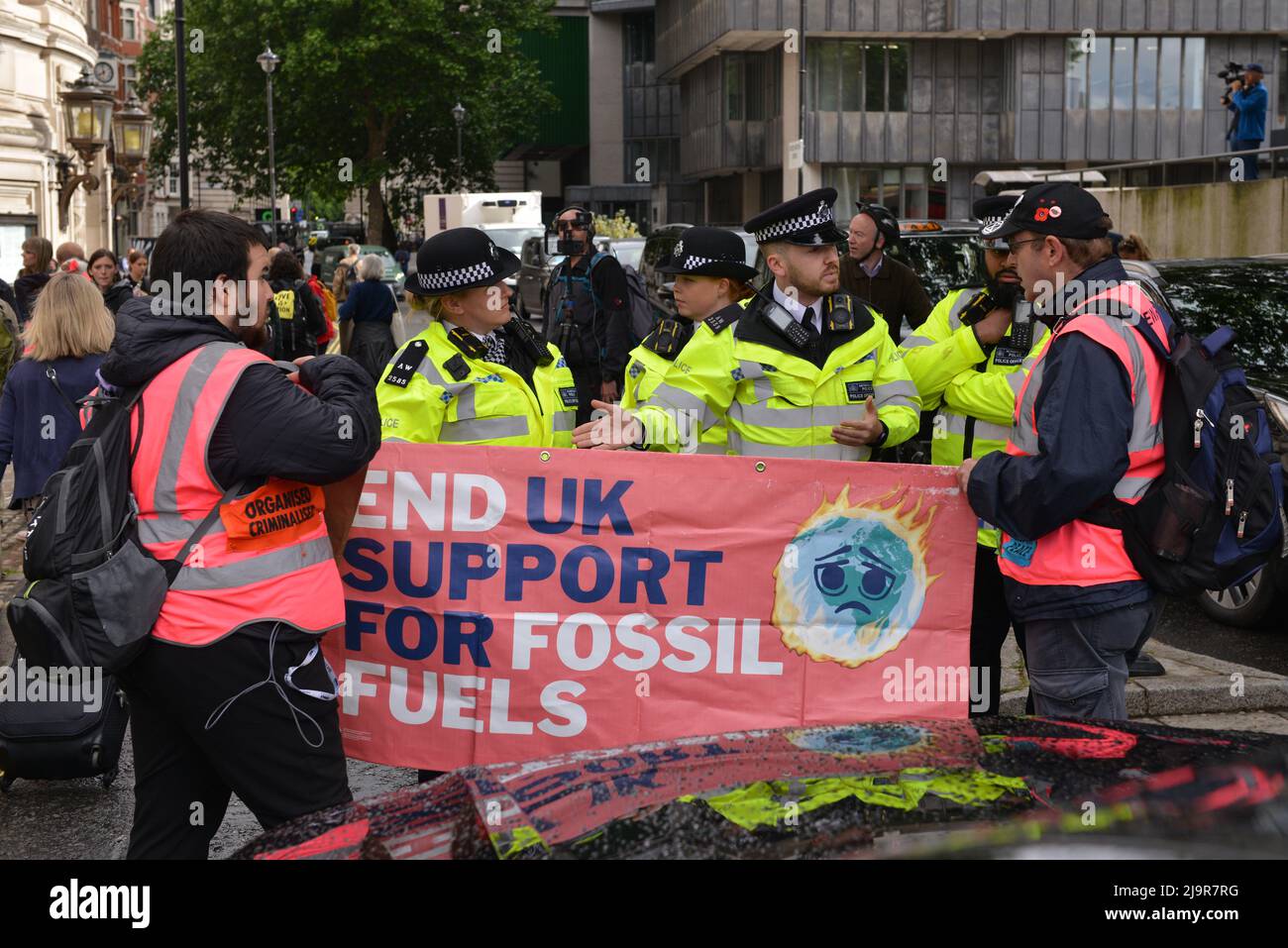 Police Officers are stopping protesters from blocking the street. Extinction Rebellion protesters gathered at Methodist Central Hall Westminster in London, to stop Shell Annual General Meeting. Stock Photo