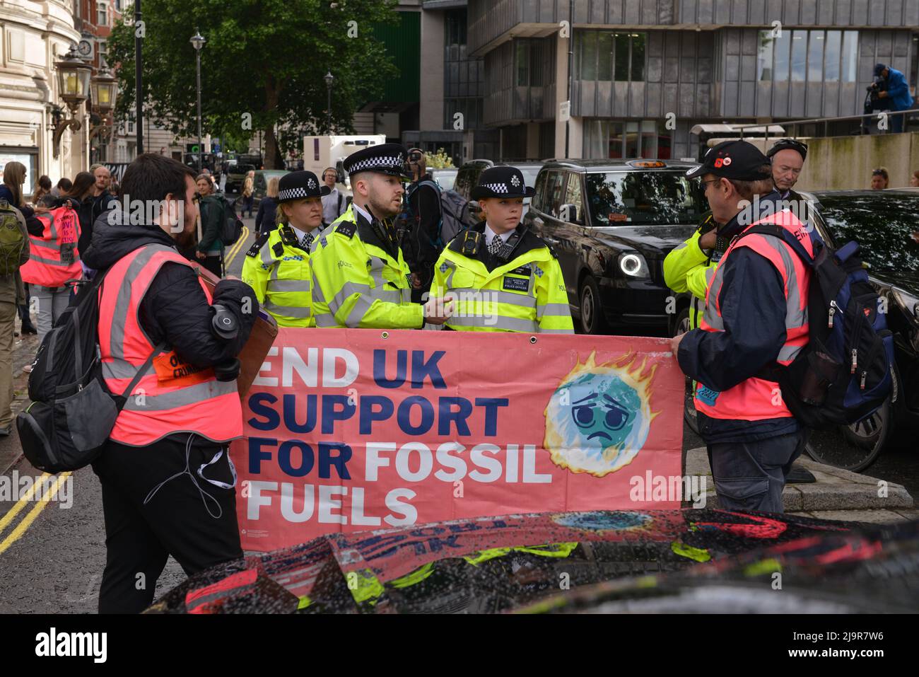 Police Officers are stopping protesters from blocking the street. Extinction Rebellion protesters gathered at Methodist Central Hall Westminster in London, to stop Shell Annual General Meeting. Stock Photo