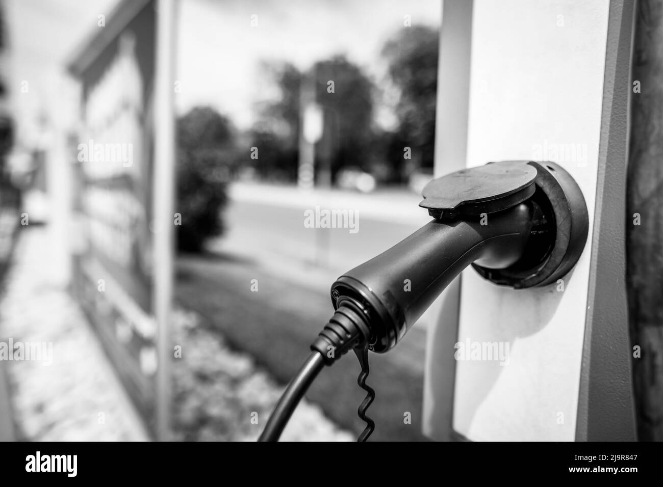 Shallow depth of field (selective focus) details with auto electric plug or socket at an electric vehicle charging station. Stock Photo
