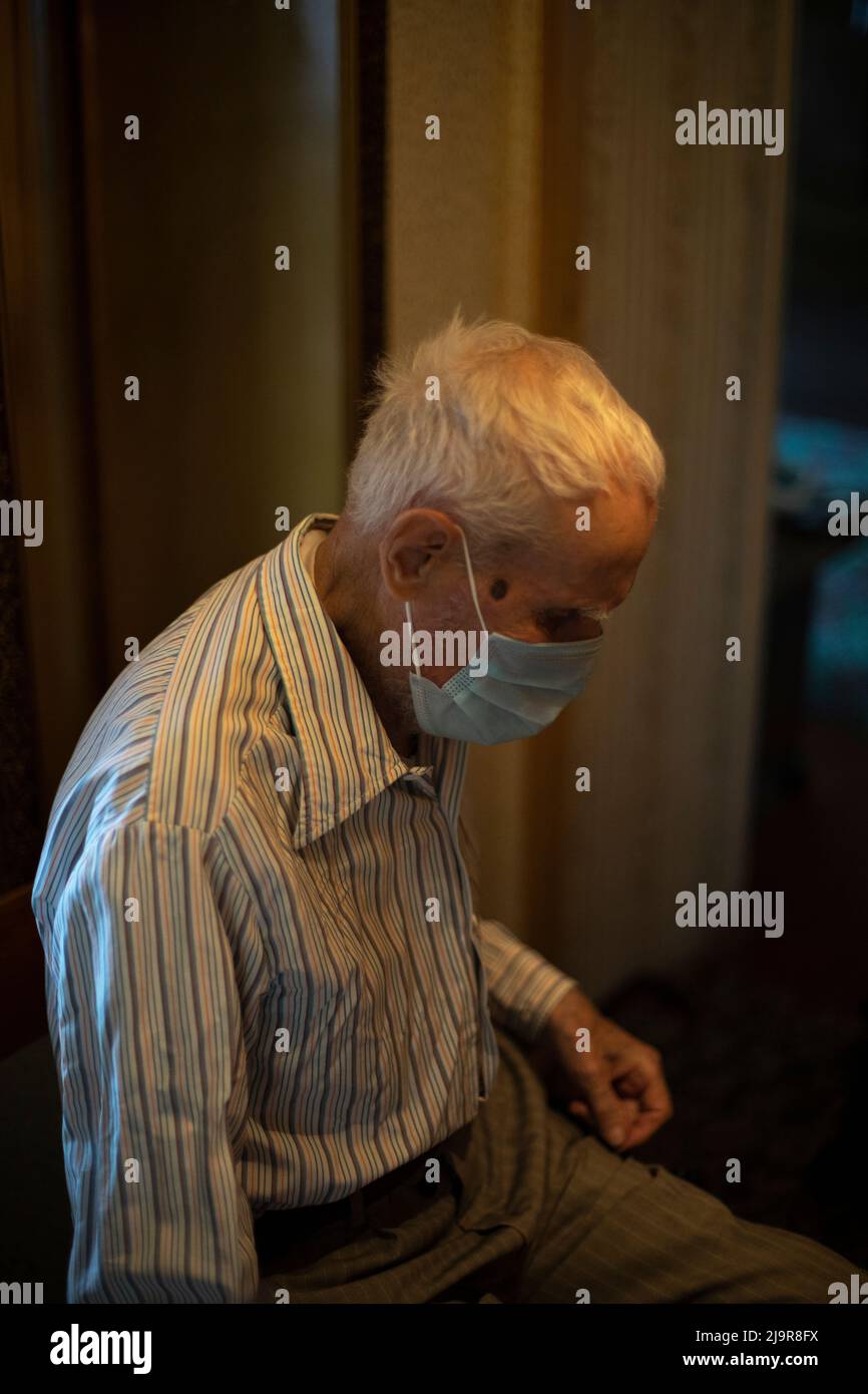 Old man in mask. Elderly man in apartment. Pensioner in house. Grizzled man. Man of 90 years. Stock Photo