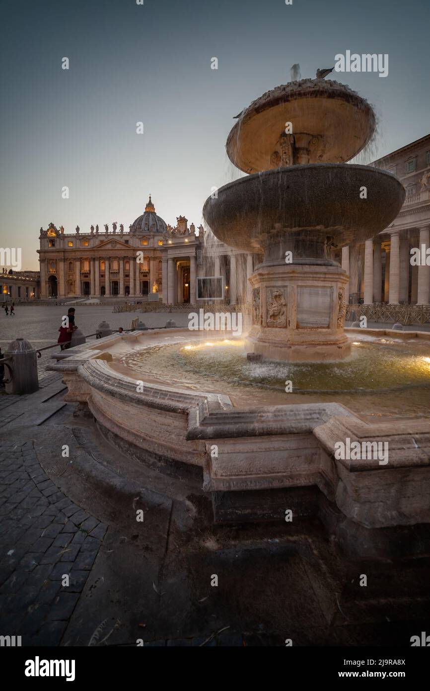 Vatican City, Maderno Fountain (1613), colonnade and St Peter Basilica at Saint Peter Square in early evening. Stock Photo