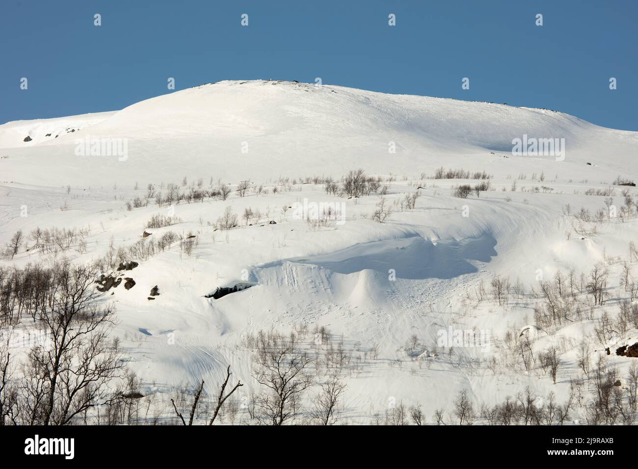 Scandinavian Mountains in March. Bright sunshine, thaw on the hillside