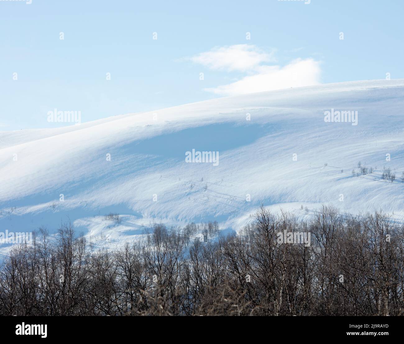 Scandinavian Mountains in March. Bright sunshine, thaw on the hillside