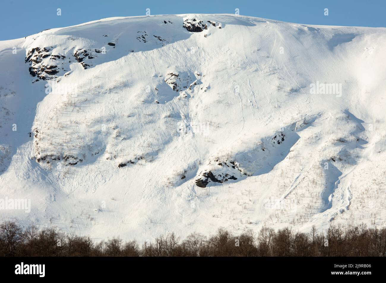 Scandinavian Mountains in March. Bright sunshine, thaw on the hillside