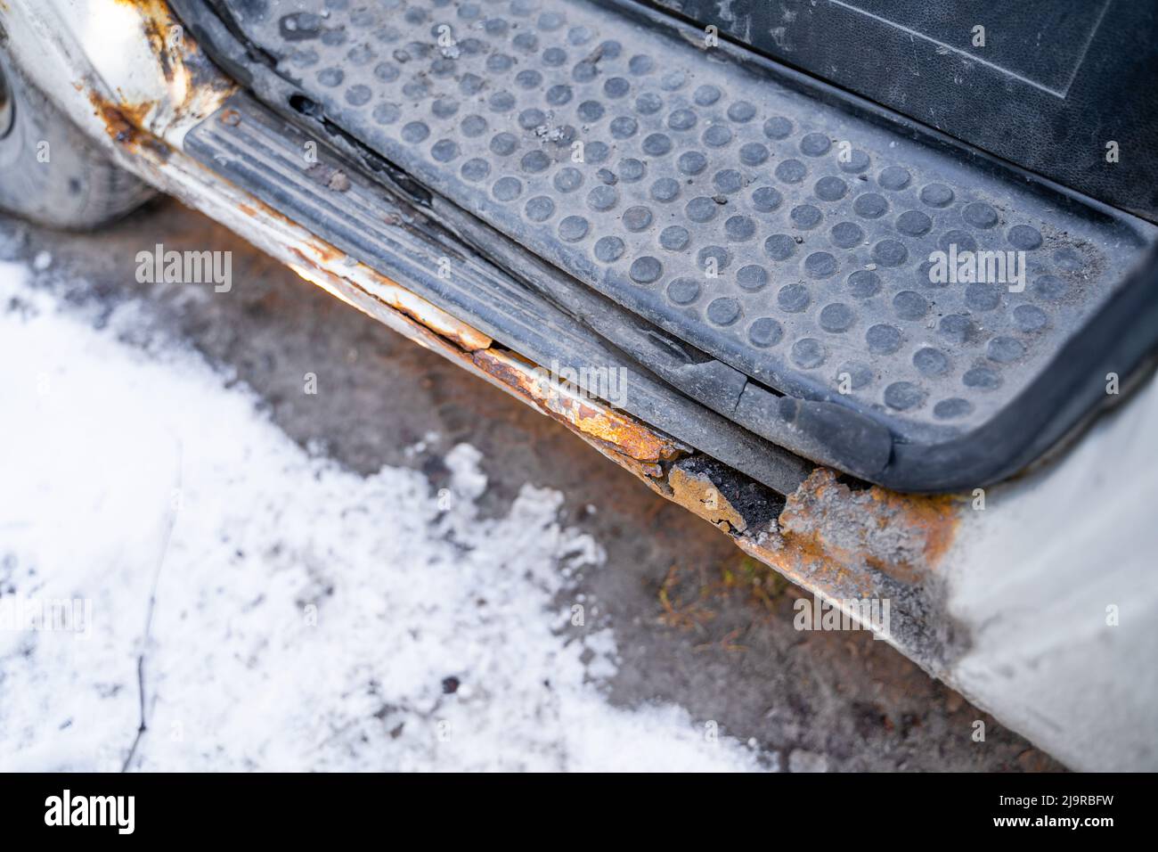 Rotten car footboard. Rusty driver's door sills. Corrosion of the car