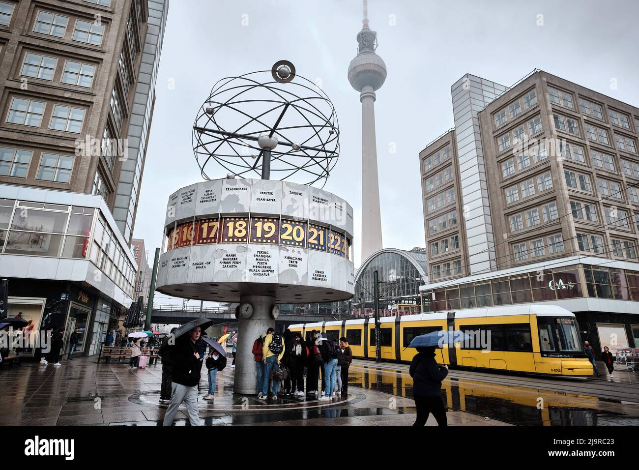 Berlin, Germany. 15th Apr, 2022. People stand while it rains under the  world time clock on Alexanderplatz in Mitte. In the background you can see  the Berlin TV tower. Credit: Stefan Jaitner/dpa/Alamy