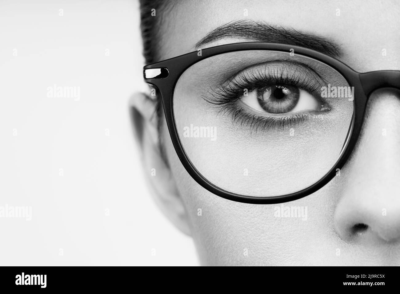 Female eye with long eyelashes in eyeglasses. Model in glasses. Vision correction. Poor eyesight. Spectacle frame. Makeup, cosmetics, beauty. Close up Stock Photo