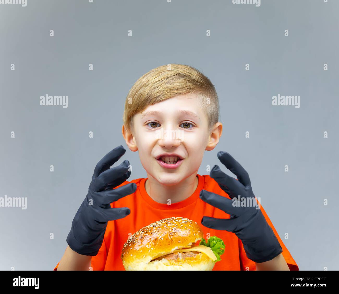 surprised boy sits in front of a huge burger and shows his hands