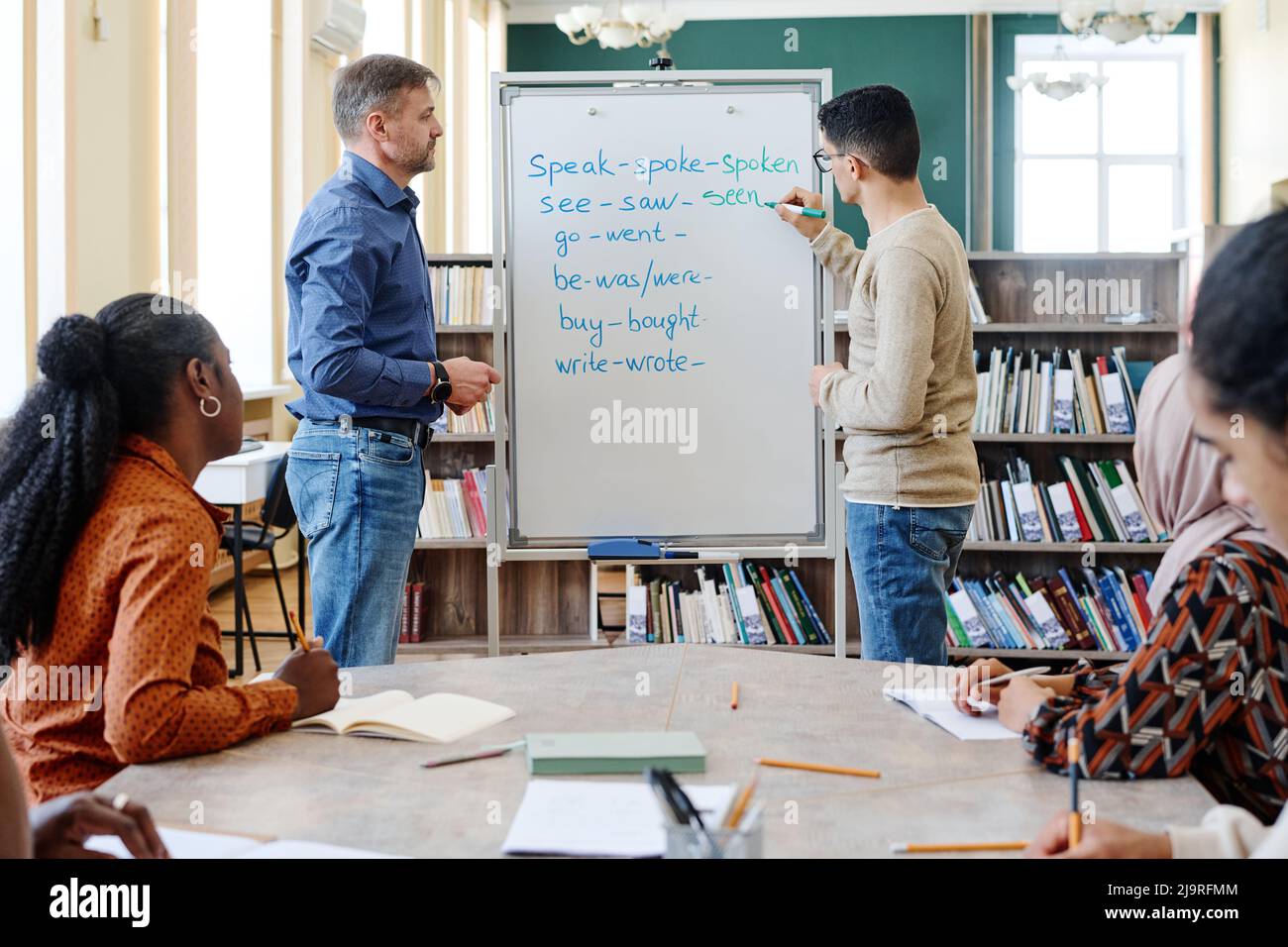 Group of modern immigrant students learning irregular verbs of English Language at school Stock Photo
