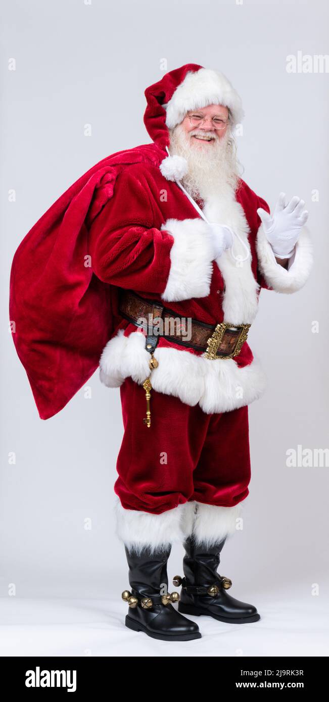 Full-length portrait of Santa Claus waving and carrying large bag Stock ...