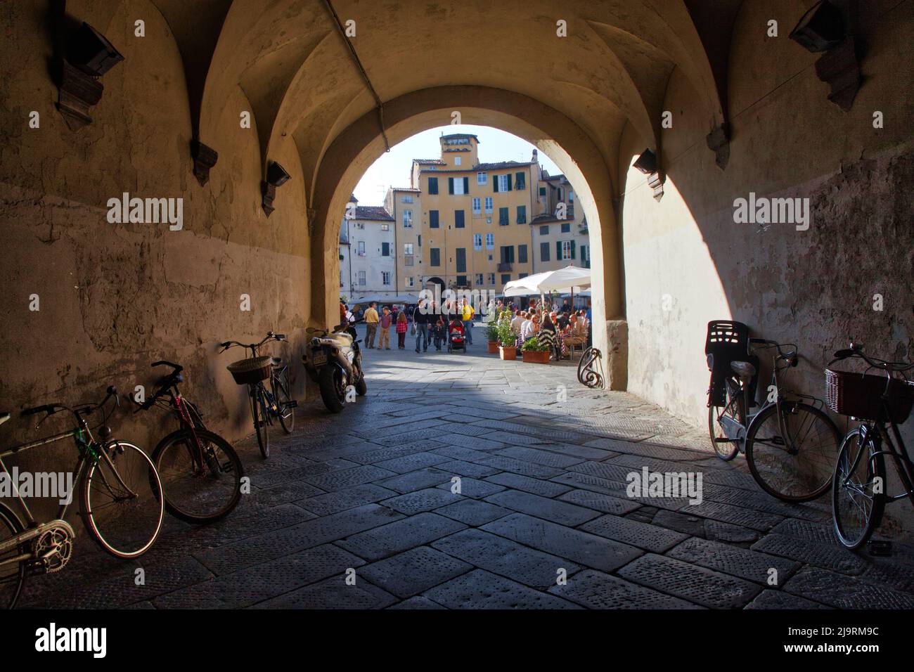 Italy, Tuscany, Lucca. Tunnel entrance to the Piazza dell'Anfiteatro Romano, lined with bicycles. Stock Photo