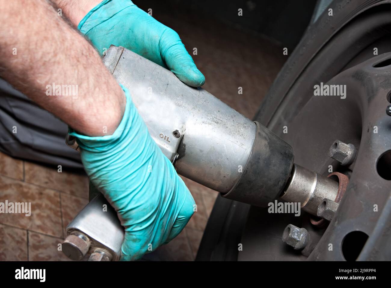 Mechanic changing wheel on car with impact wrench. mechanic man with