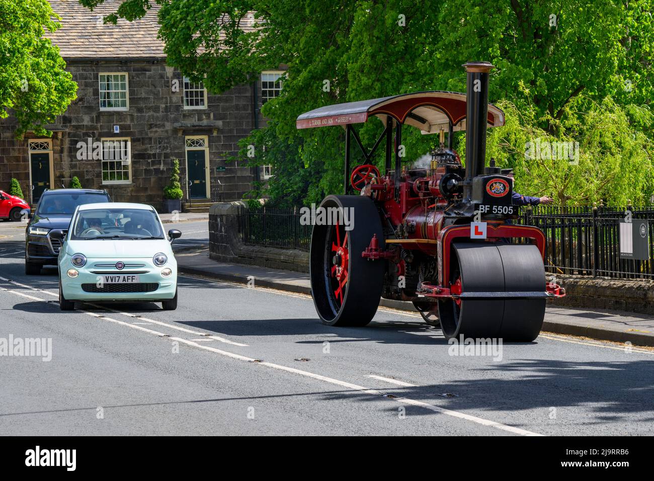 Red black stationary heavy steam-powered vehicle parked at roadside (L-plate on front) overtaken - Burley-in-Wharfedale, West Yorkshire, England, UK. Stock Photo