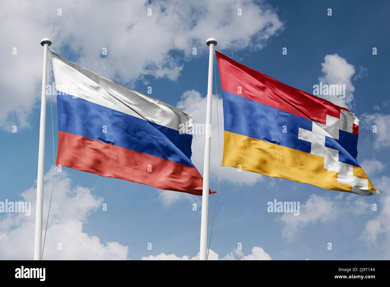 Russia and Artsakh two flags on flagpoles and blue cloudy sky background Stock Photo