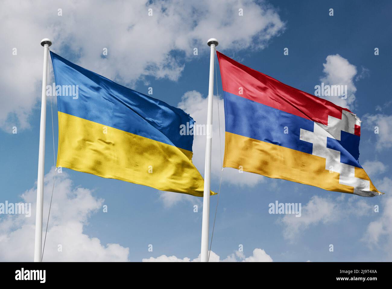 Ukraine and Artsakh two flags on flagpoles and blue cloudy sky background Stock Photo
