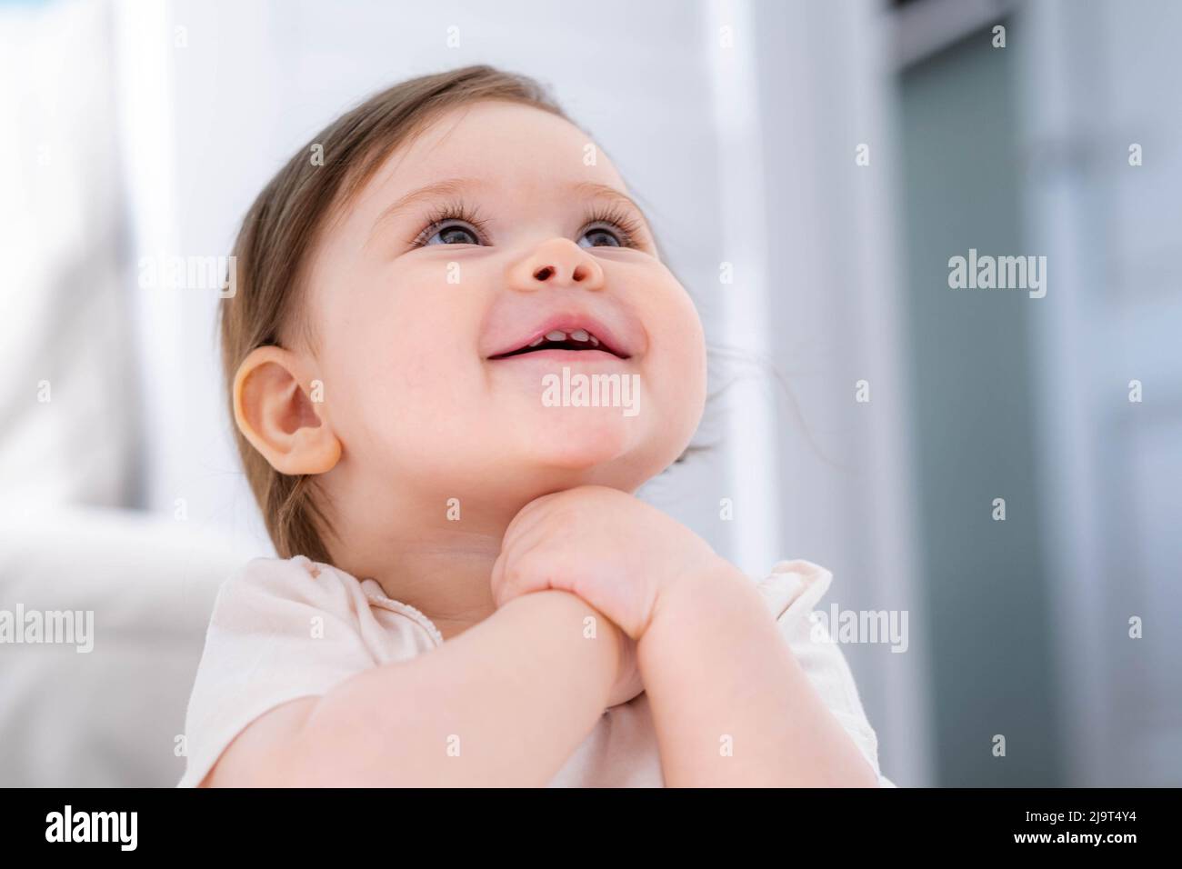 Excited cute little baby girl thinking of something dreaming or having a good idea, smiling and looking up, imagination. Stock Photo